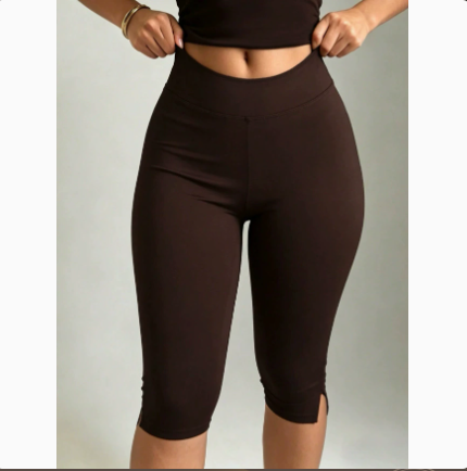 Woman in brown high-waisted slim-fit capri leggings with hands at the waistband, front view