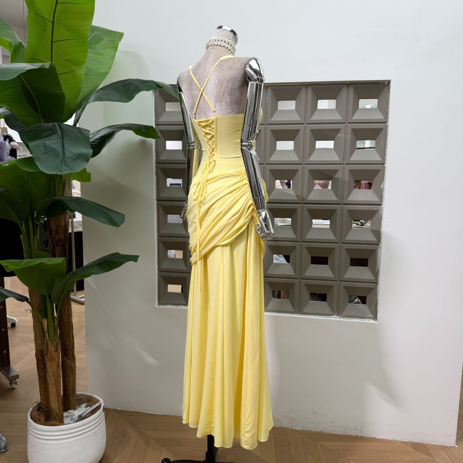 Back view of the butter yellow maxi dress on a form, laced centre panel and flared skirt