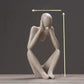 Sandstone finish abstract resin meditator figurine with height arrows on a dark backdrop
