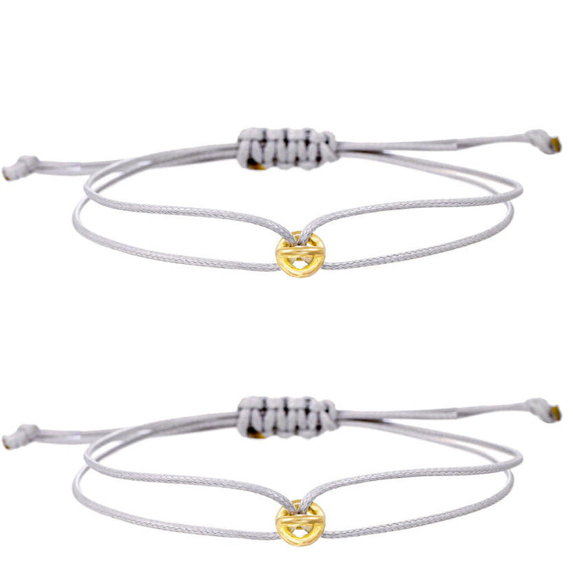 Two light gray cord bracelets with small gold tone charms and adjustable slide knots