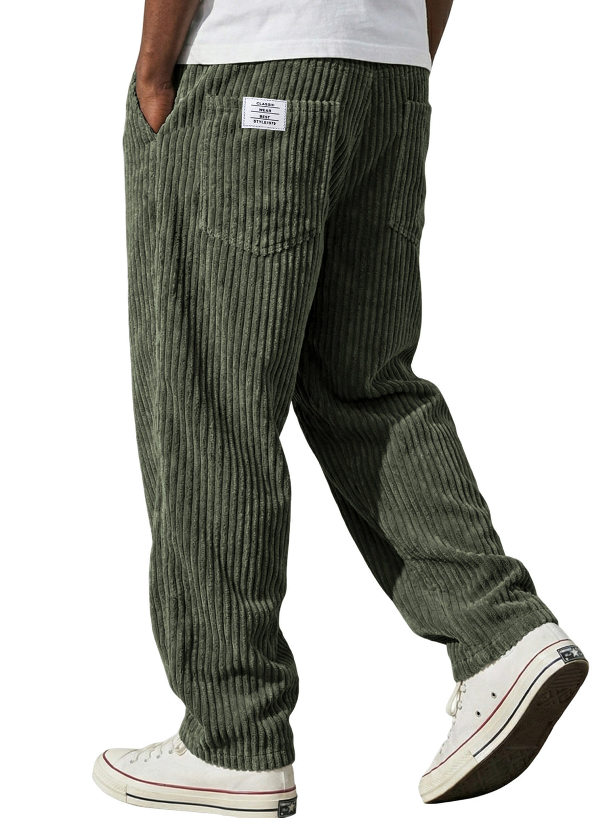 Side view of the loose straight corduroy trousers falling clean over white trainers