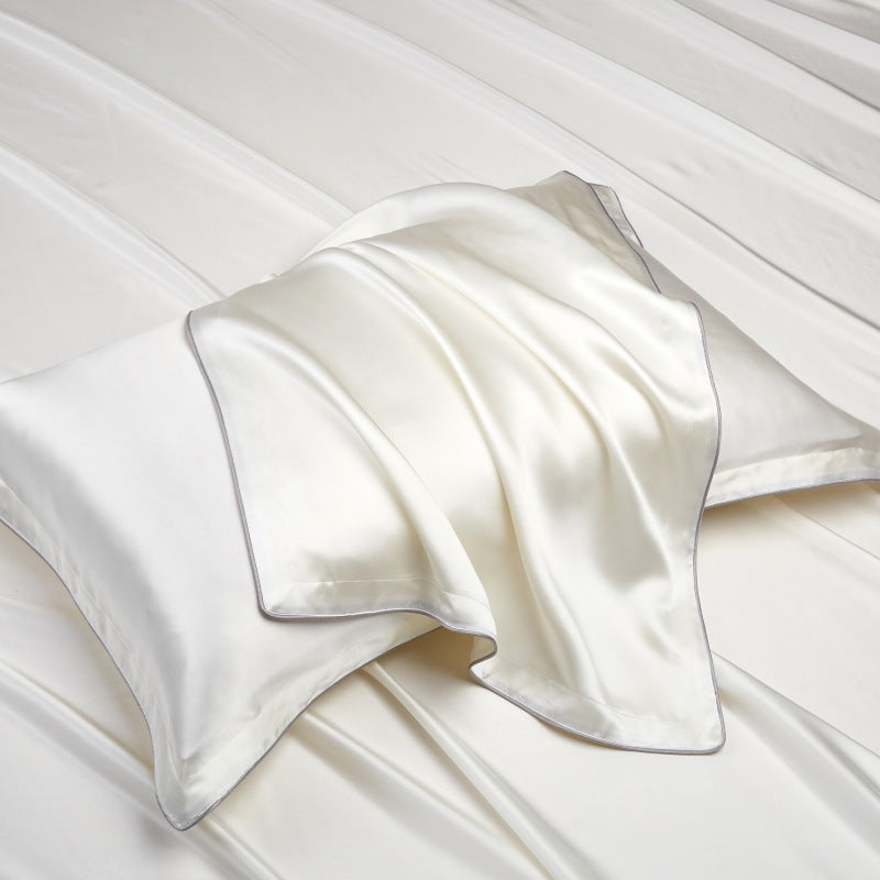 Lustrous silk pillowcase with a soft sheen and piped edge on pale bed linen