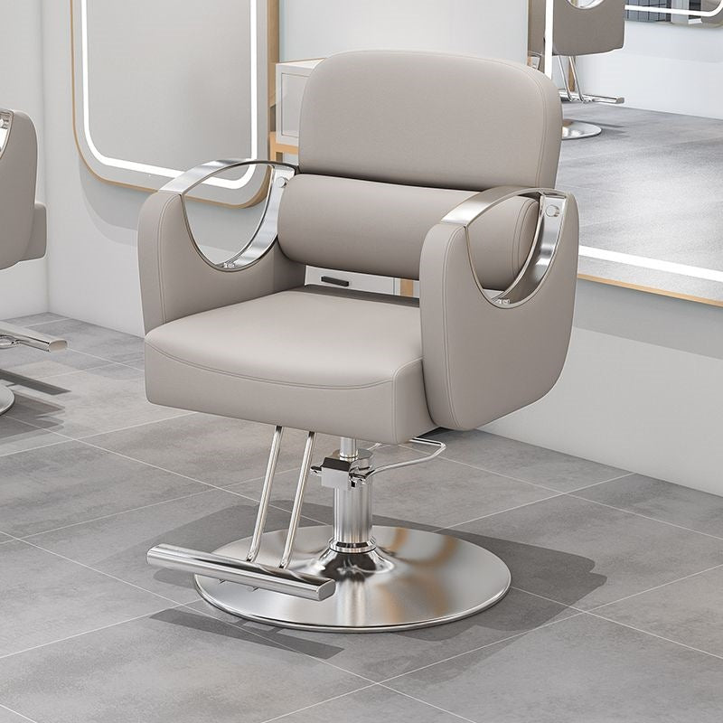 Black salon styling chair with curved gold metal armrests on a gold disc base in a salon