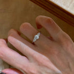 Sterling silver cubic zirconia ring worn on a finger, round faceted center stone flanked by small accent stones