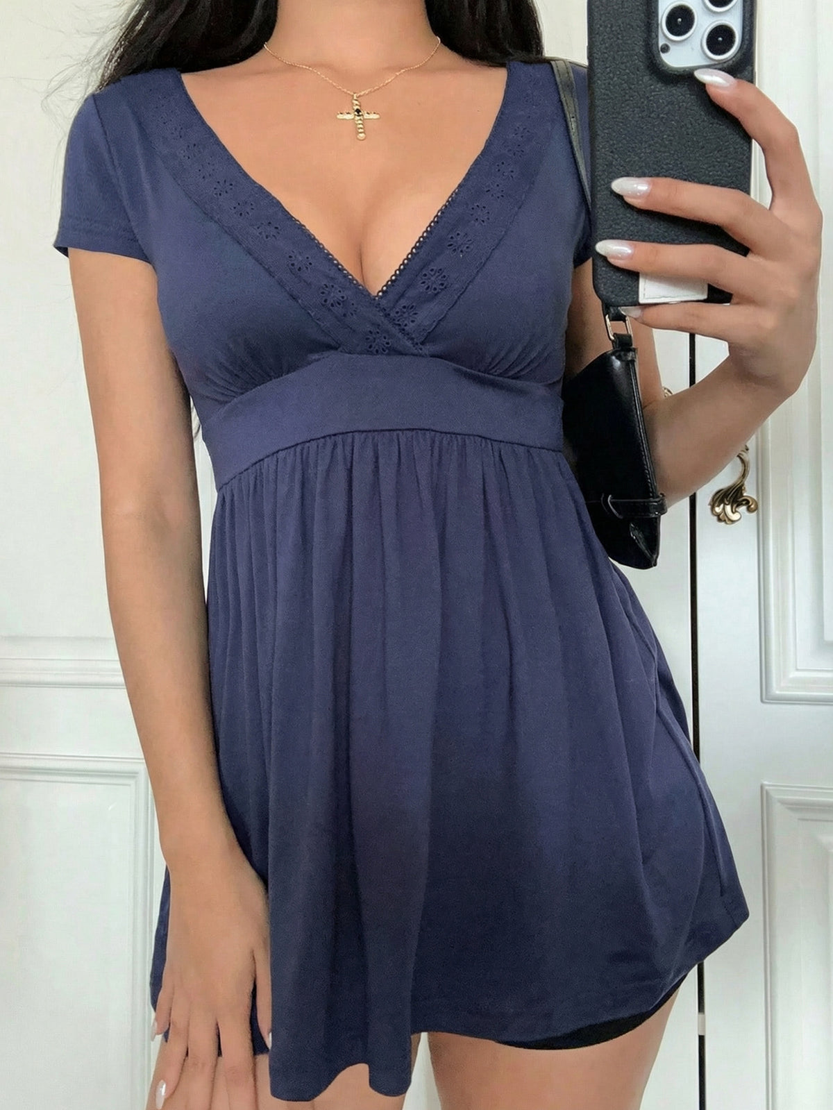 Navy deep V-neck babydoll top with eyelet lace trim shown close up on a model