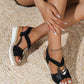 Black snakeskin wedge sandal showing the elastic slingback strap and white rubber outsole