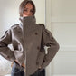 Side view of the taupe double breasted wool blend coat showing epaulettes and cuff tabs