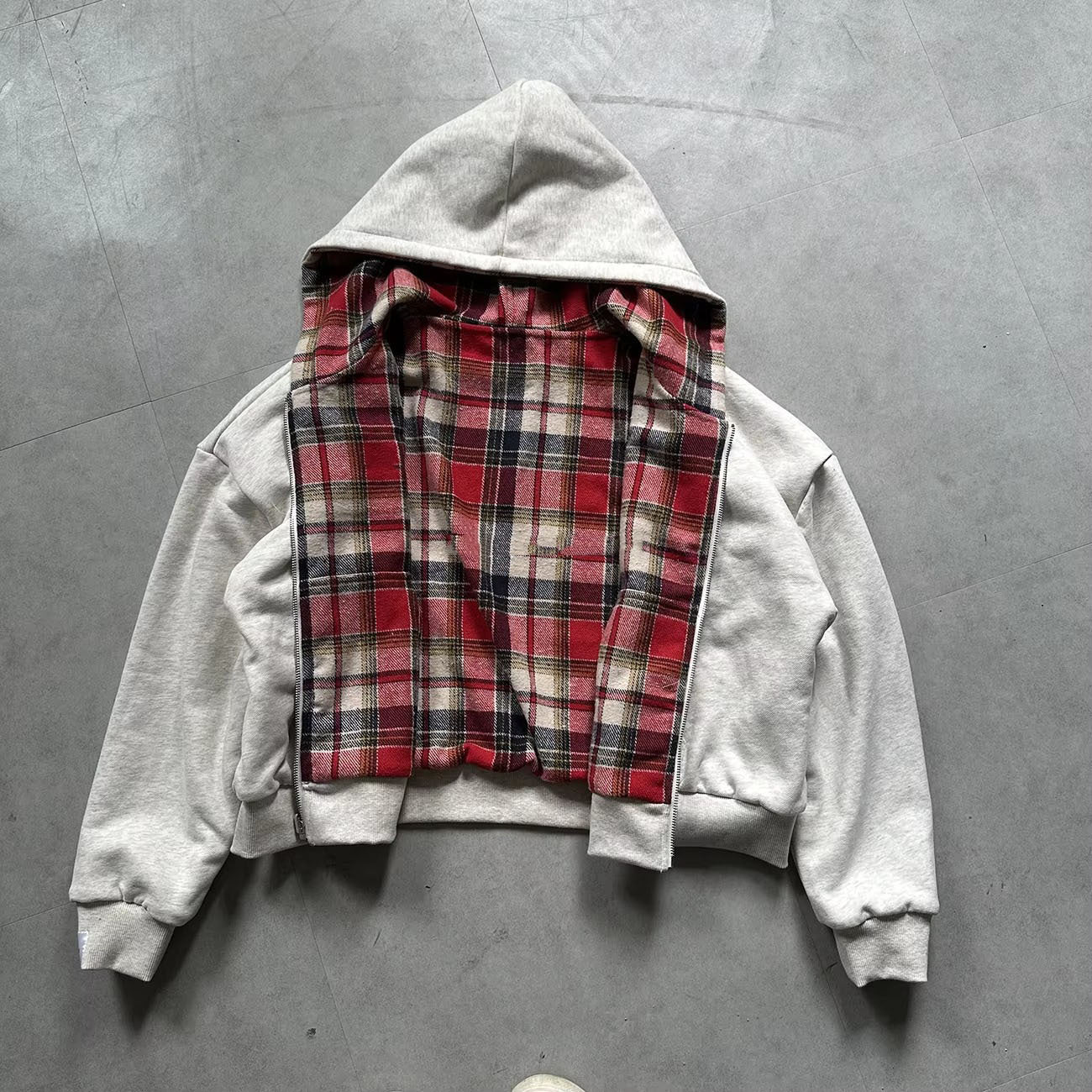 Grey reversible zip hooded sweatshirt, solid grey outer with a red tartan plaid reverse