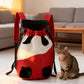 Red and cream pet carrier backpack standing on a living room floor beside a tabby cat