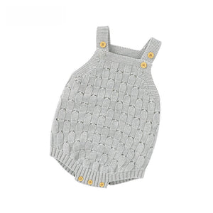 Pink knit baby romper showing the buttoned shoulder straps and open pointelle pattern