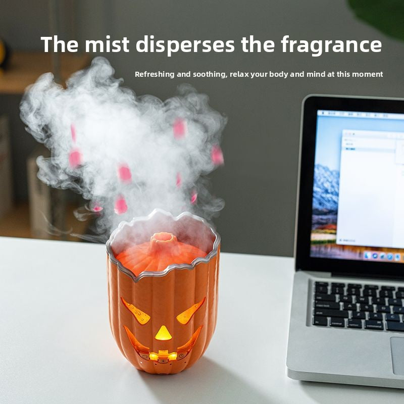 Pumpkin diffuser on a white desk beside a laptop sending up a plume of cool mist