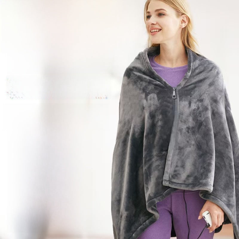 Woman in the dark gray flannel heating shawl with a center zip and a cord with a small controller held in her hand
