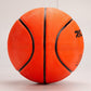 Side view of the orange rubber basketball with curved black channels and a printed logo on a gray background