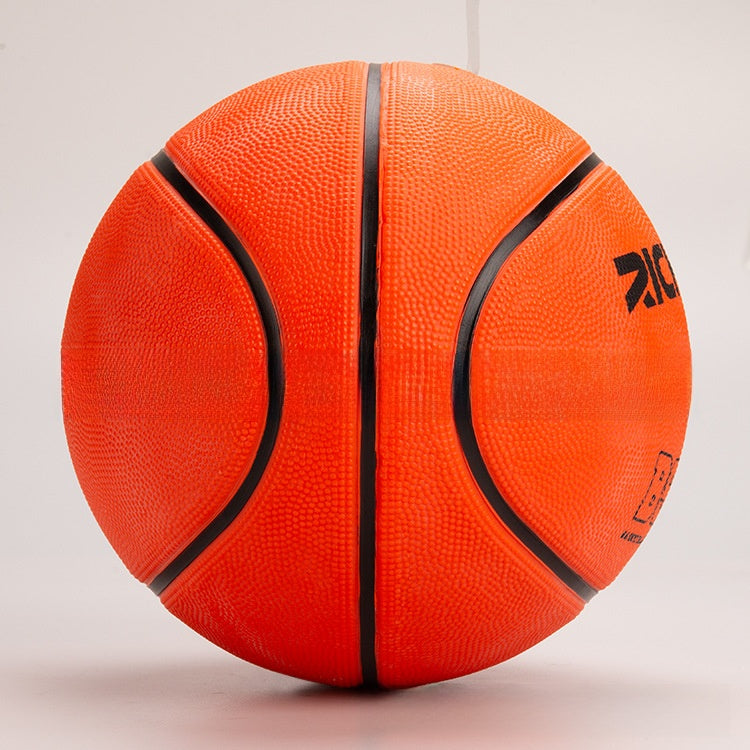 Side view of the orange rubber basketball with curved black channels and a printed logo on a gray background