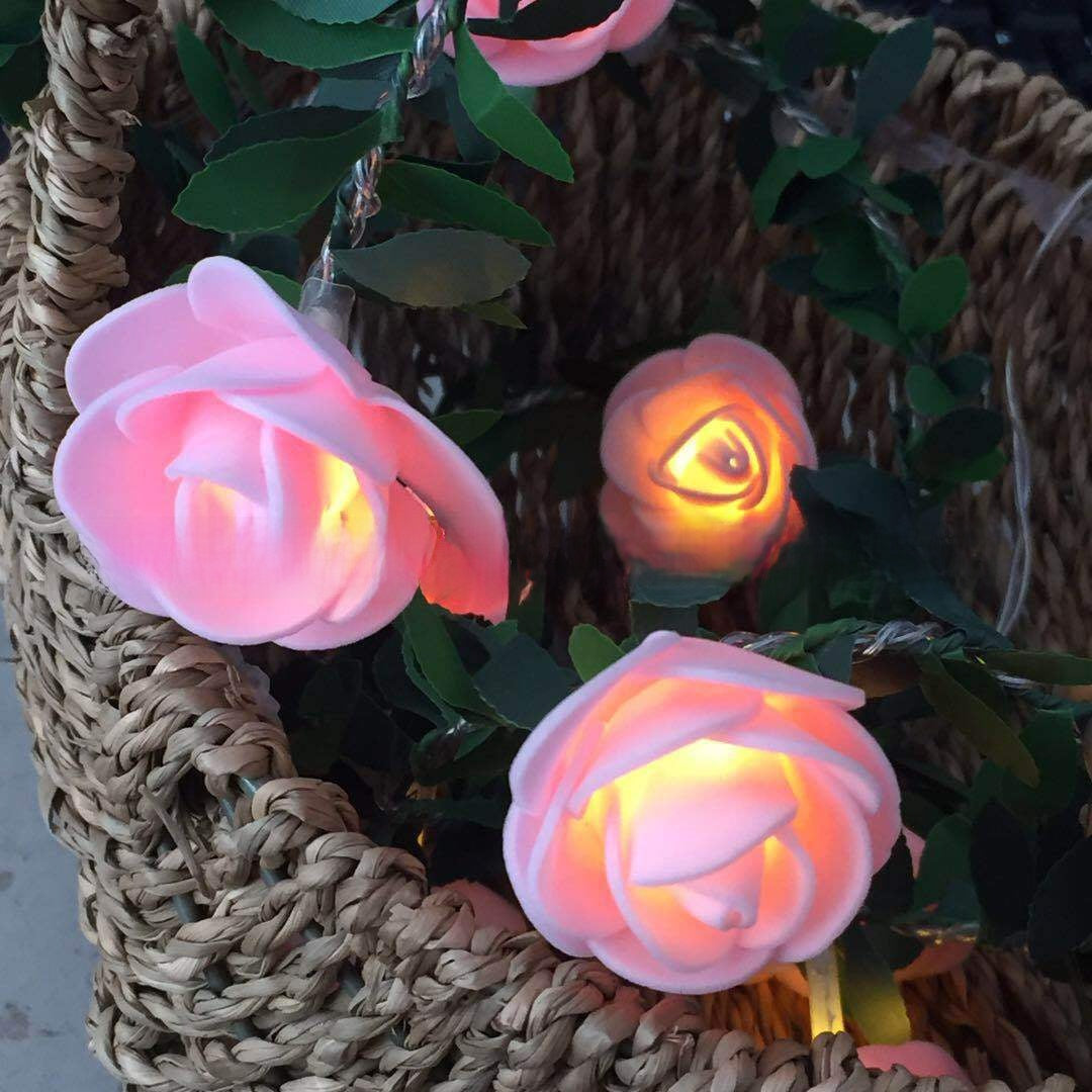 Pink flower LED fairy string light on a green leaf vine with a warm glow, decorative photo