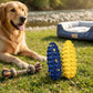 Golden retriever lying on grass beside a blue and a yellow bumpy corn cob dog toy, a rope toy and a dog bed