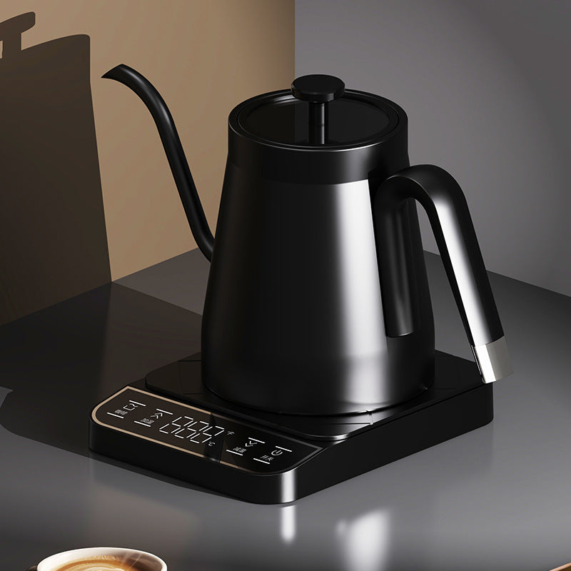 Black gooseneck electric kettle on its touch base on a dark counter, cup of coffee in the foreground