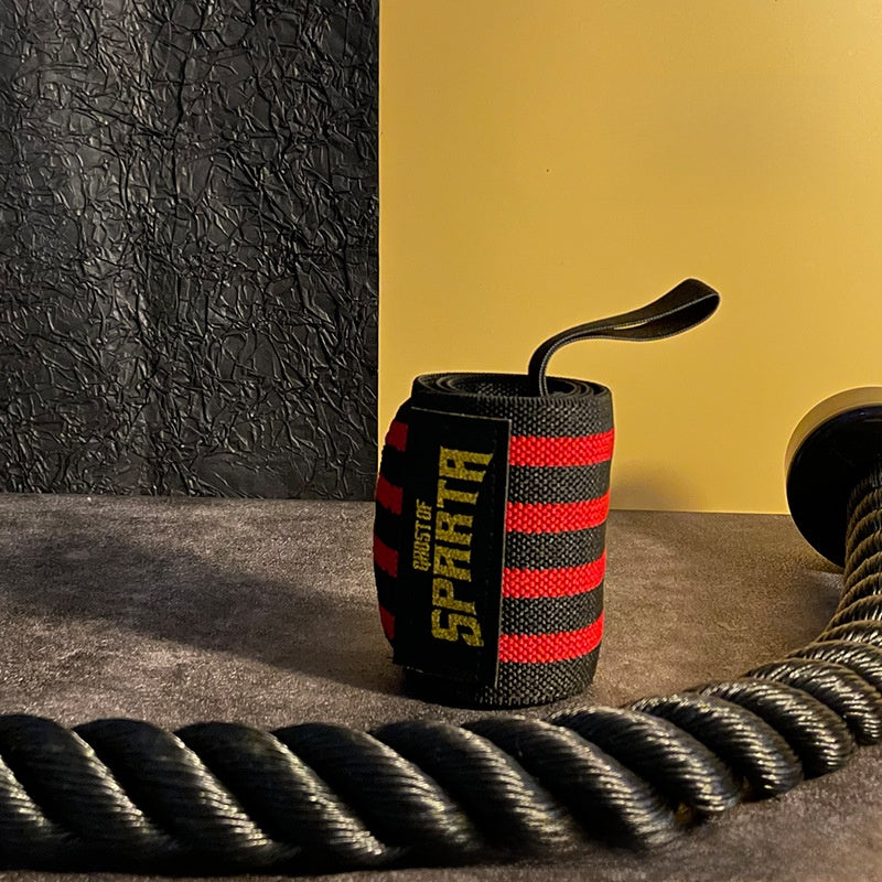 Black and red elastic wrist wrap rolled beside a training rope, thumb loop up