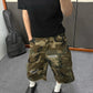 Camo ripped denim cargo shorts worn with white socks and black clogs, side cargo pocket and torn window visible