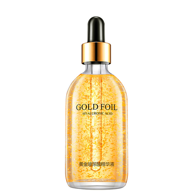 Clear facial essence dropper bottle with suspended 24k gold foil flakes on white
