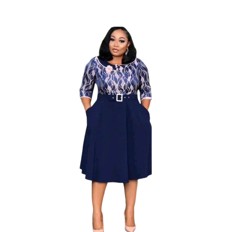 Woman in a navy belted midi dress with printed bodice and pleated swing skirt, front view