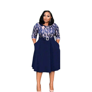 Woman in a navy belted midi dress with printed bodice and pleated swing skirt, front view