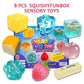 Eight squishy toys laid around the open blue box, cheese cube, bread, butter stick and gel cubes