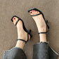 Close-up of black square toe sandals with a thin band over the toes and an ankle strap
