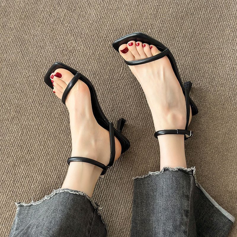 Close-up of black square toe sandals with a thin band over the toes and an ankle strap