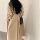 Back of the light khaki long trench coat showing the loose drape and back waist tab