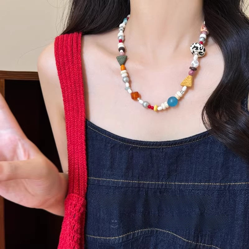 Colorful beaded clavicle necklace worn over a denim top, close collarbone view