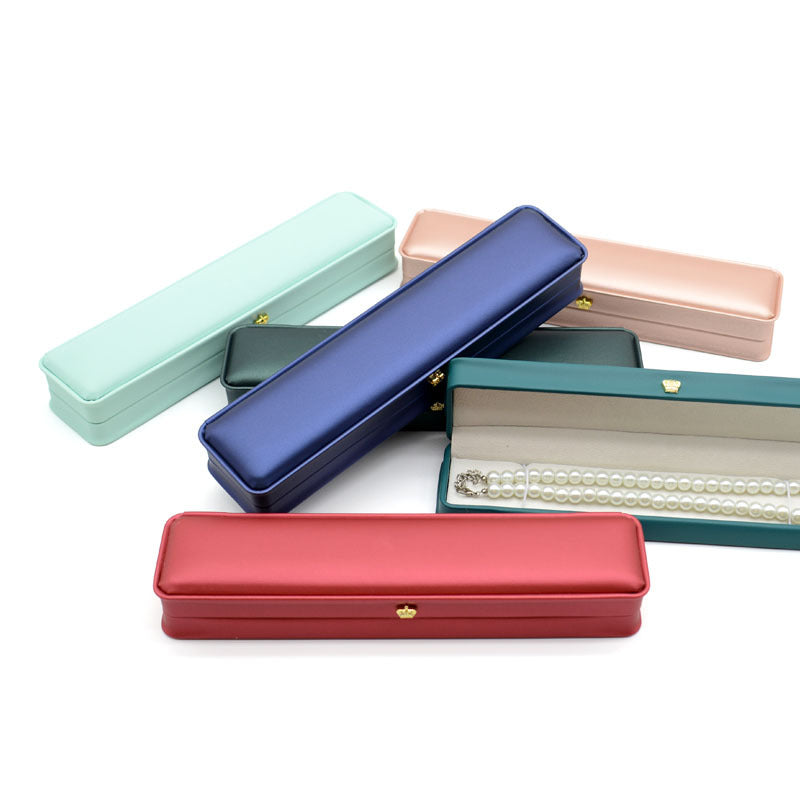 Several crown clasp necklace boxes shown flat, with an open burgundy box holding a pearl strand