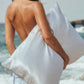 Woman holding a silver white silk pillowcase on a beach, sea salt stripe option