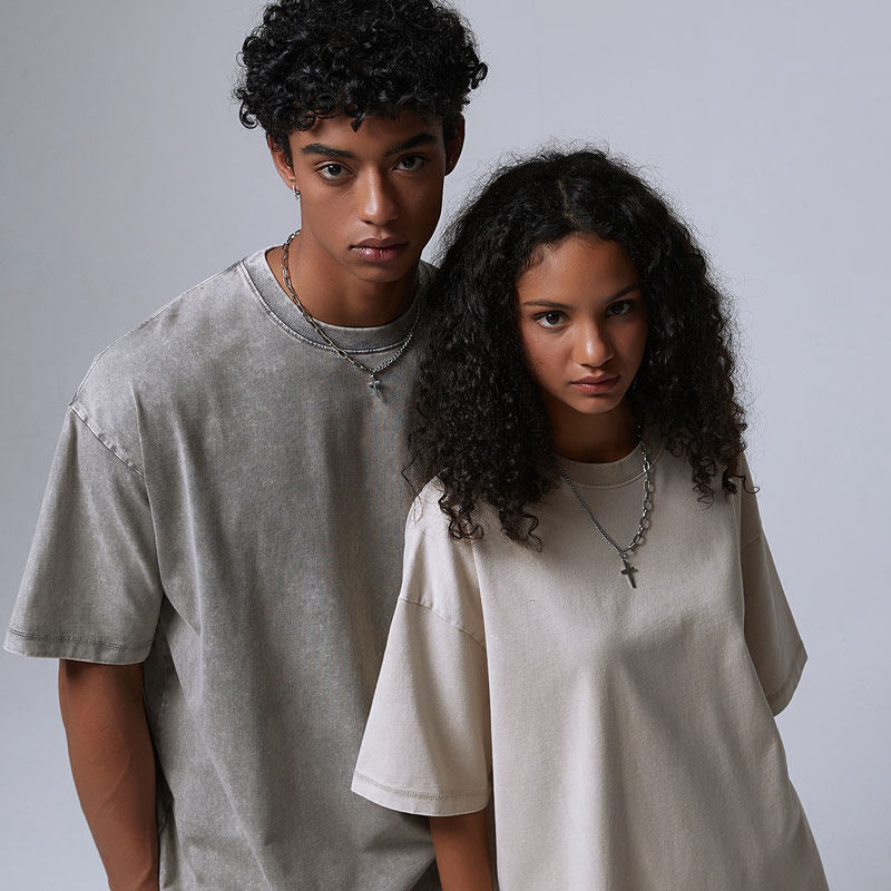 Man in a washed light gray t-shirt beside a woman in a cream washed t-shirt, loose dropped-shoulder fit