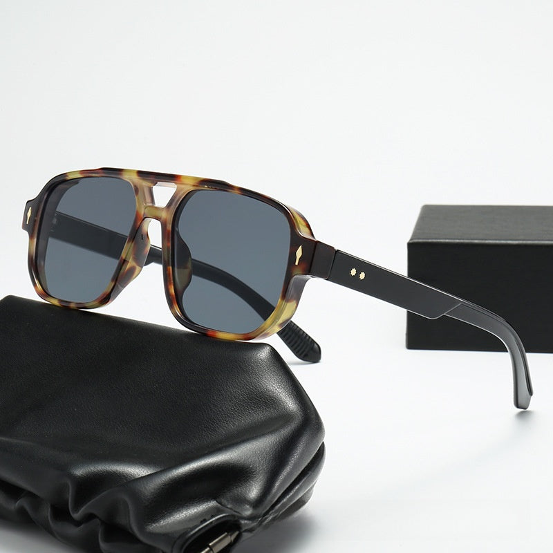 Square double bridge sunglasses with a tortoise frame and gray lenses beside a gift box