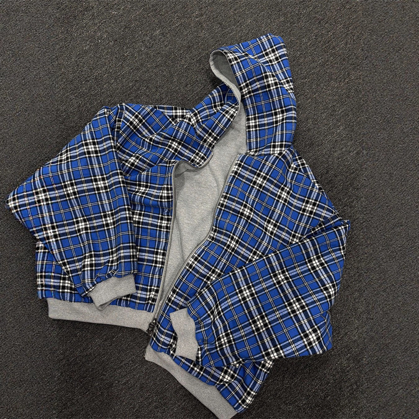 Grey reversible zip hooded sweatshirt, solid grey outer with a blue tartan plaid reverse
