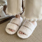 Pair of plush open toe slide slippers with two soft bands over the foot on a bed