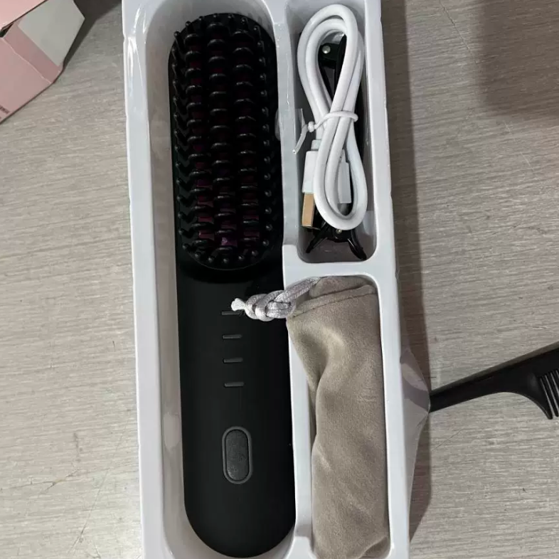 Black cordless straightening comb with a white USB charging cable shown inside the open retail box tray