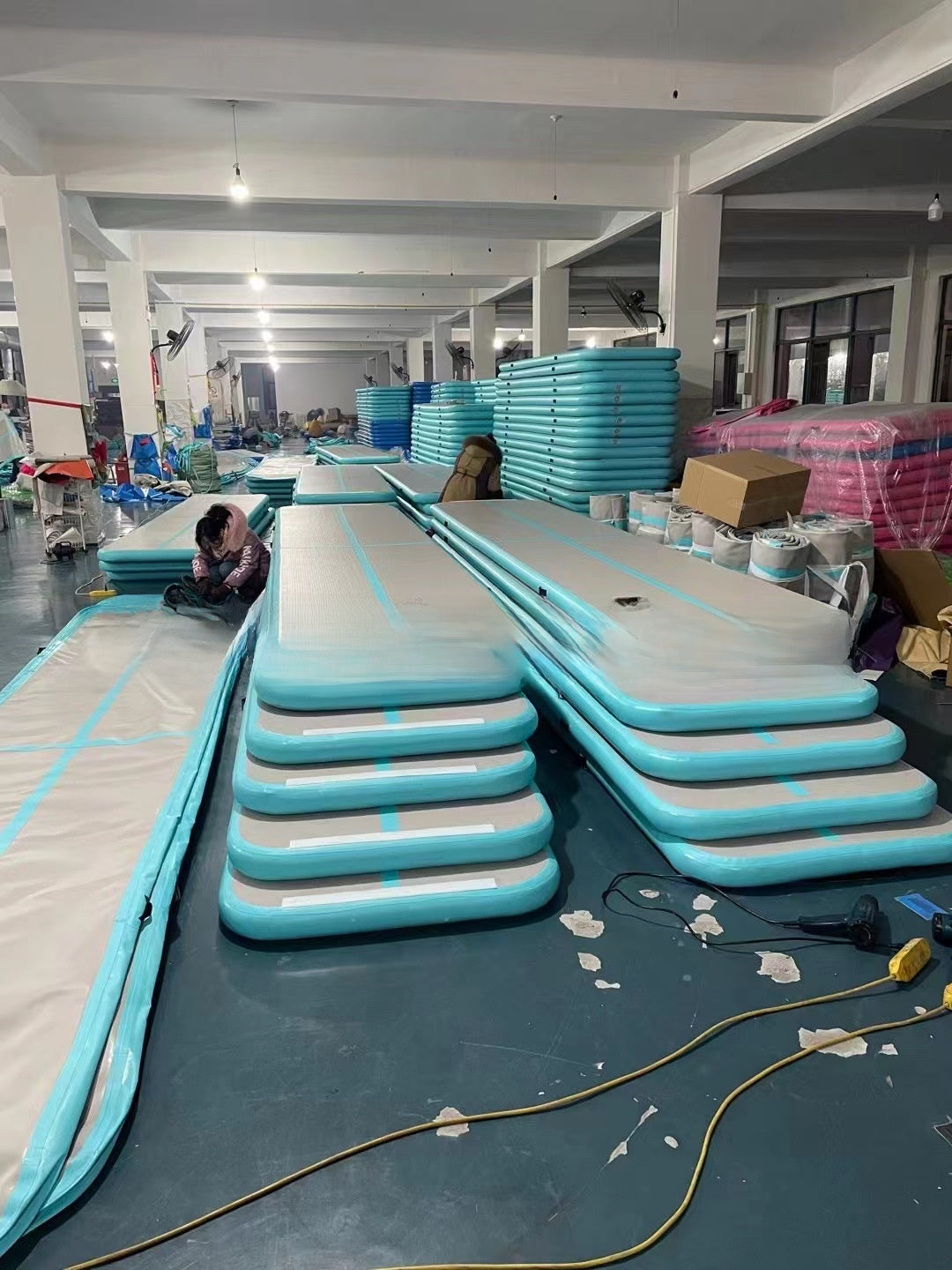 Stacks of mint green inflatable air track mats in a warehouse, 5 x 1 x 0.1 m option photo
