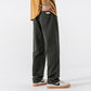 Green straight leg cotton pants in size L, side view with a hand in the pocket and low sneakers