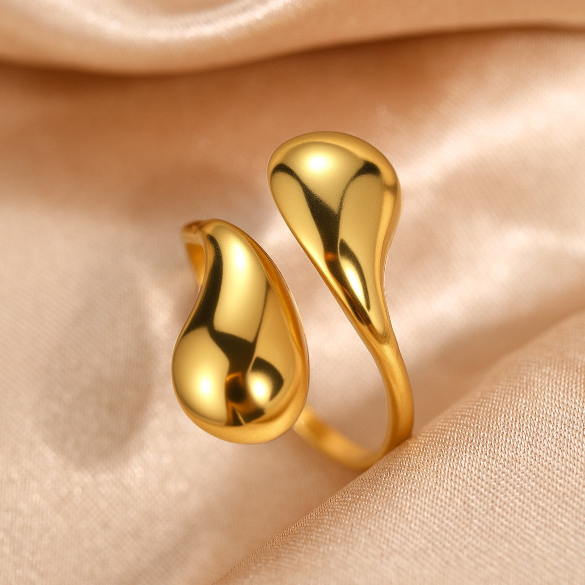 Gold water drop bypass ring shown on satin with the two drops catching light