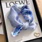 Light blue geometric printed square scarf with a satin sheen and hemmed edges, shown displayed