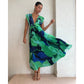 Model in the green abstract pleated maxi dress leaning against a wall