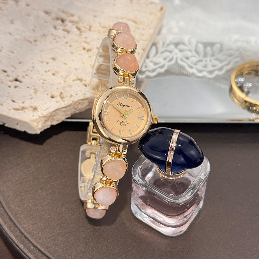 Wrist view of the beaded bracelet watch with a small vintage gold dial