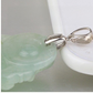 Macro of a pinch-bail finding gripping a pale green stone pendant