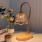 Retro candle warmer lamp with a tulip shade and a light wood base on a table beside flowers and a jar