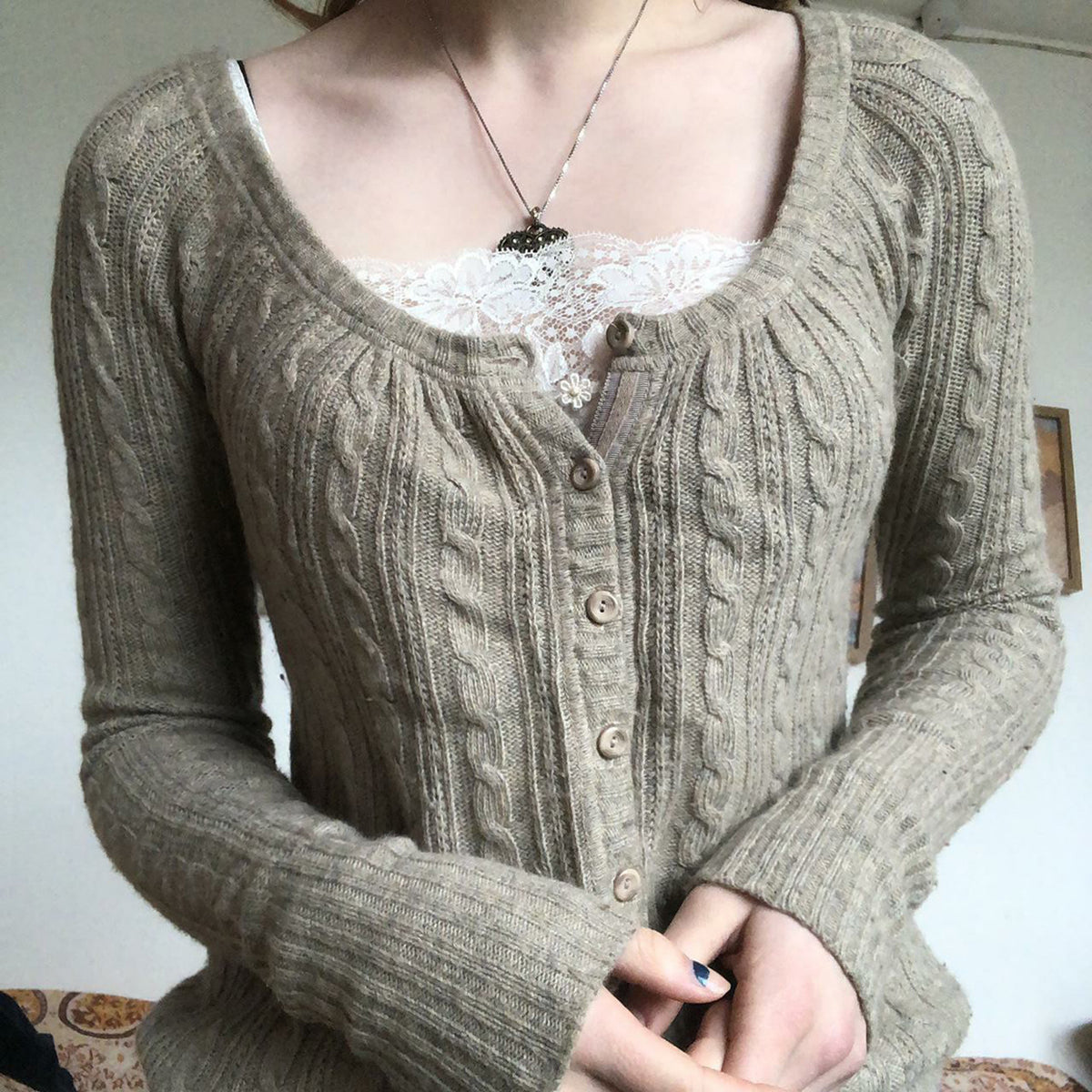 Close up of the khaki cable knit cardigan with a gathered scoop neckline and round tonal buttons