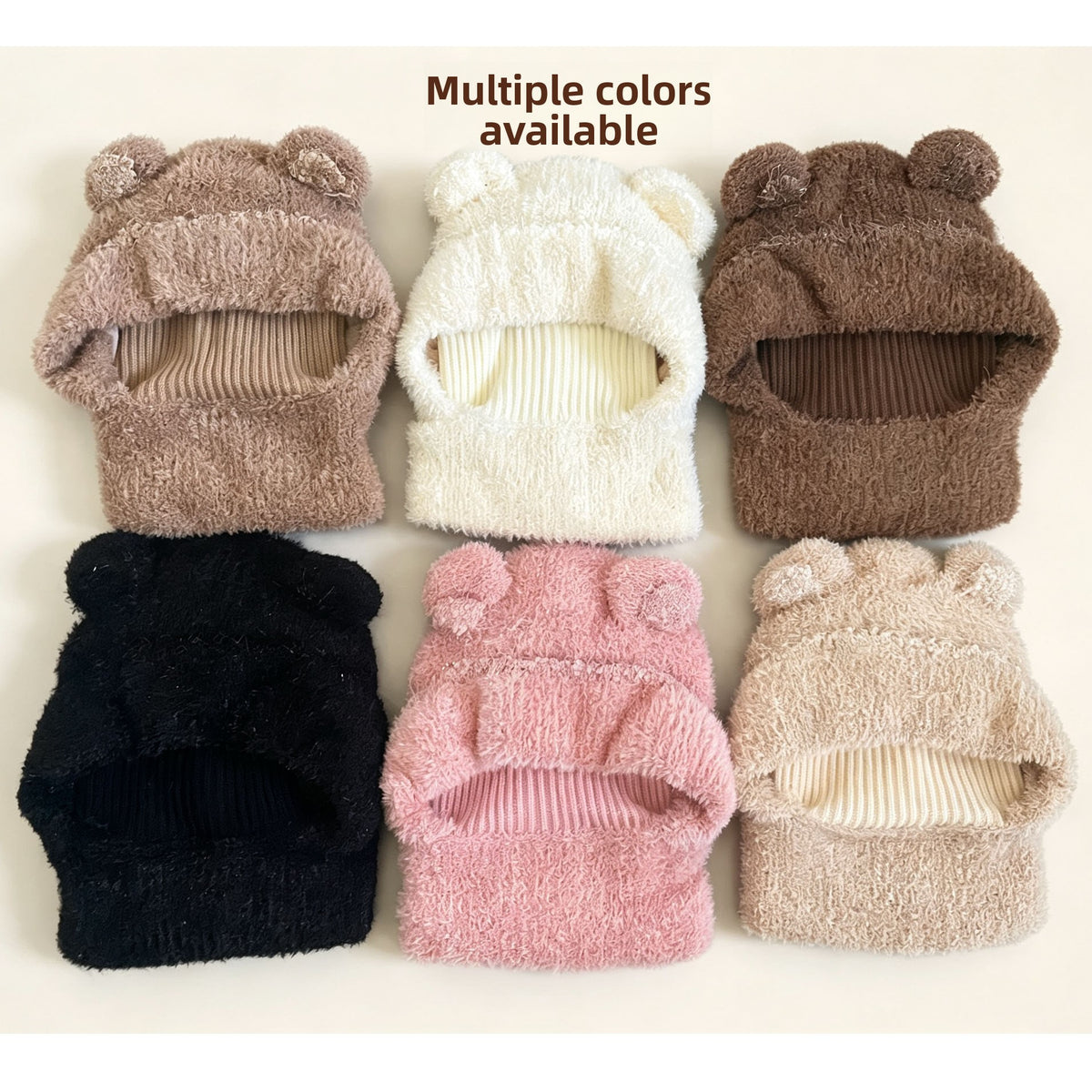 Six colours of fluffy knit bear ear balaclava hoods laid out: mocha, cream, brown, black, pink and beige