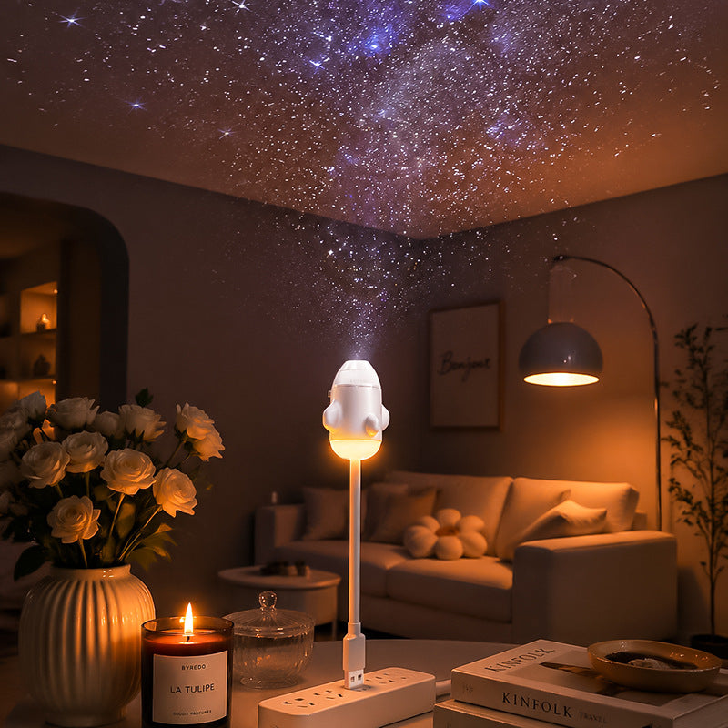Star projector on a table casting a dense star field across a living room ceiling