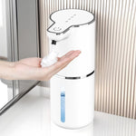 White sensor soap dispenser on a basin surround, a dome of foam landing on an open hand